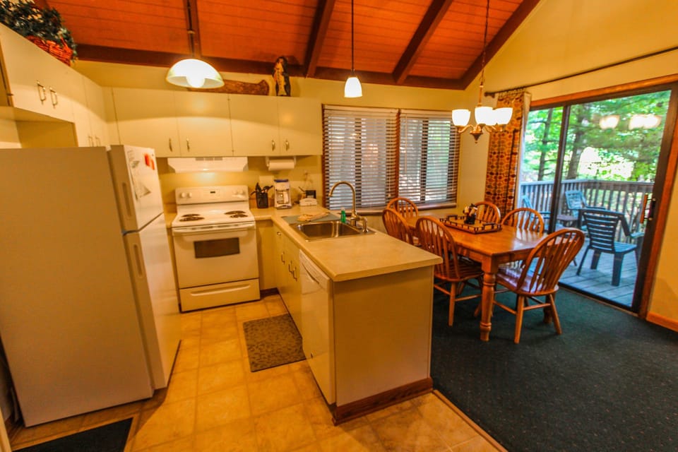 The cozy and fully equipped kitchen features a dining area that opens up to a private deck, perfect for a peaceful family retreat.