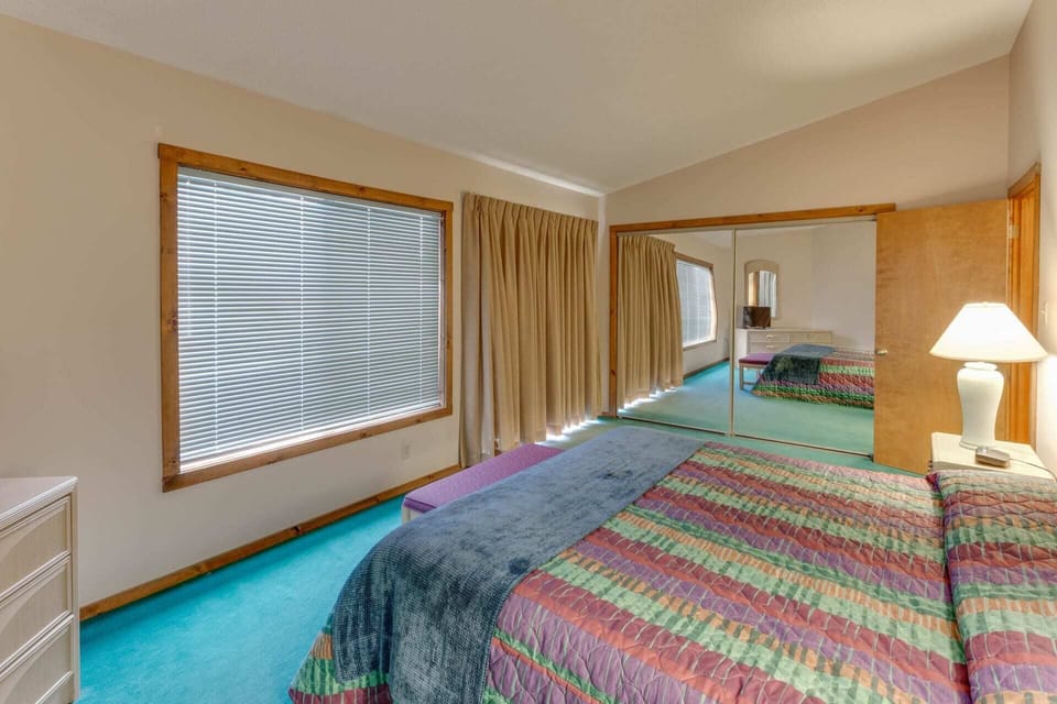 Upper-level bedroom with a queen bed and mountain views through large windows.