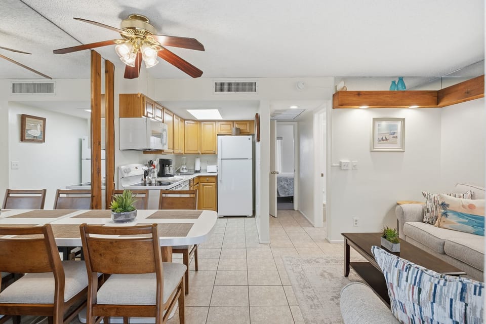 An open-concept layout connects the kitchen, dining, and living areas beneath a ceiling fan for a bright, airy feel.