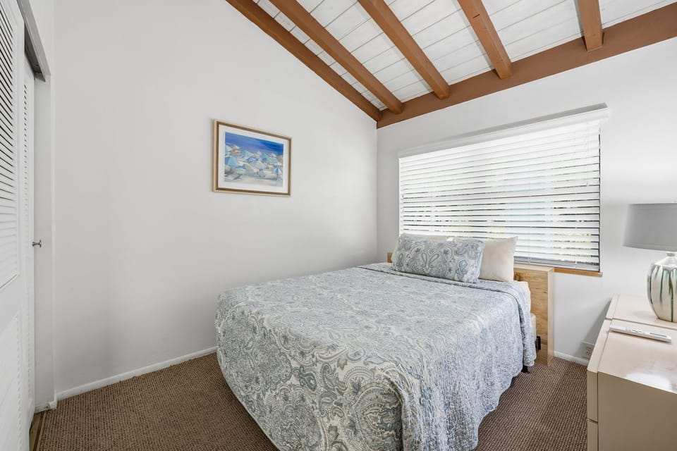 Another bedroom view highlights the queen bed, wall art, and a cozy layout filled with natural light.
