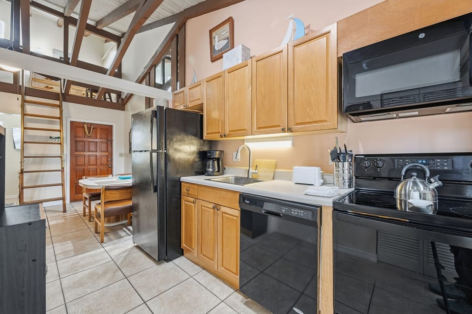 A closer look at the kitchen highlights modern appliances and wood cabinetry beneath the lofted sleeping area.