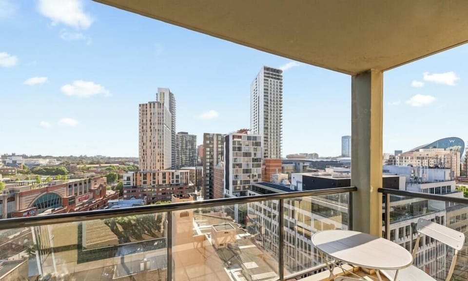 The view from a high-floor balcony furnished with a simple outdoor table and chairs