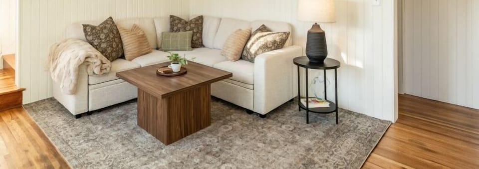 Step into this bright living space, where a cozy sleeper sectional invites relaxation. Stream your favorite shows on the smart TV, while large windows flood the room with natural light, creating a warm and welcoming ambiance.