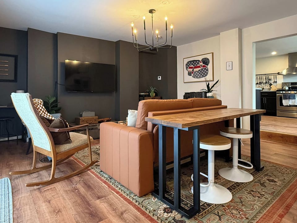 LIVING ROOM | FIRST FLOOR: Relax with your fellow travelers in our designer living room. A sofa, armchairs, and a table with bar stools accommodate any seating preference. Watch your favorite shows & movies on the Smart TV while you unwind!