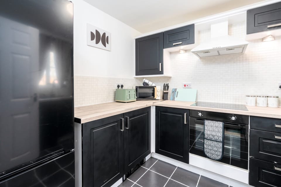 Modern kitchen with black cabinetry and wooden countertops - fully equipped for meal preparation after a long workday.