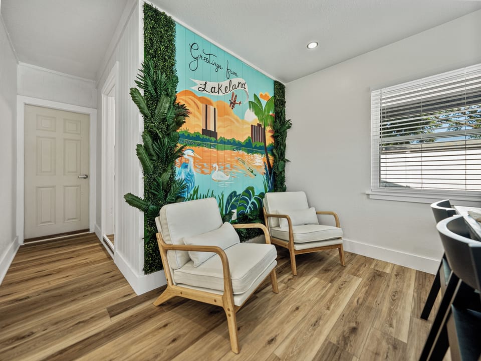 The modern dining area features sleek chairs and a minimalist table, perfect for comfort and connection. A striking mural by a local artist showcases Lakeland’s iconic lakes, landmarks, and downtown, adding a vibrant, personal touch.