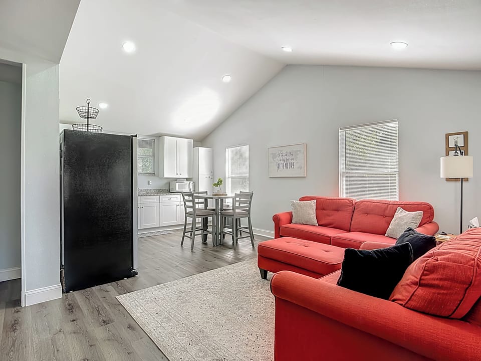 Welcome to this bright, open-concept living room and kitchen! Vaulted ceilings enhance the airy vibe, with natural light pouring in. 