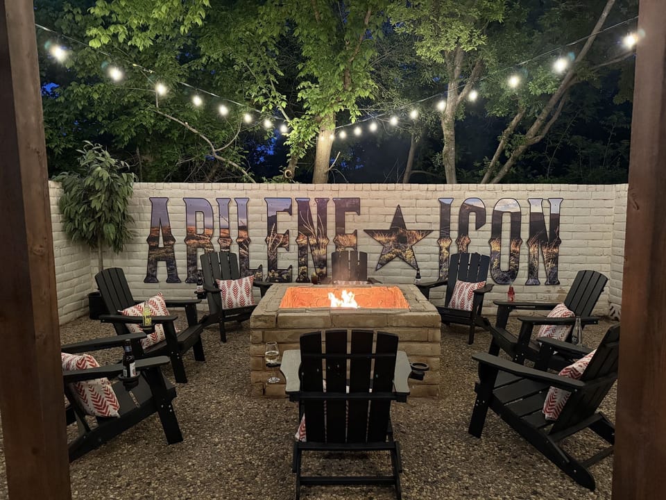 Gather 'round the campfire where the Abilene Icon mural stands tall against the rustic brick wall. As twilight falls and the string lights twinkle like stars in the Texas sky, swap tall tales or toast a marshmallow while the embers glow.