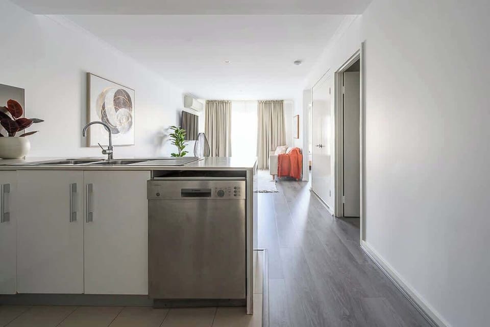 This open-concept living space features a modern kitchen with a full-sized dishwasher and sleek cabinetry. Enjoy a seamless transition from morning coffee at the island to relaxing in the sun-drenched lounge beyond.