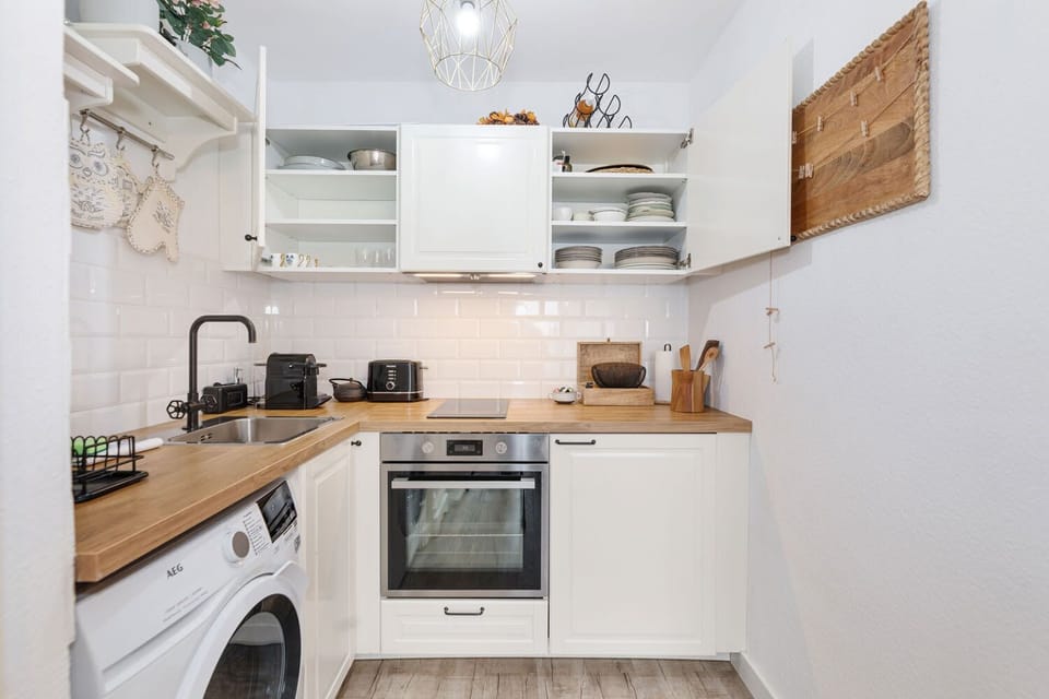 Smart storage solutions with neatly organized dishes behind classic white cabinets – everything you need within easy reach.