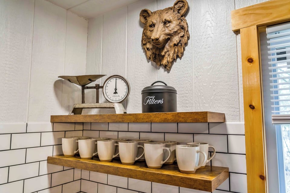 These open shelves offer a cozy, nostalgic touch with their vintage-style scale, “Filters” tin, and a full set of mugs - topped off with a carved bear accent that brings a bit of the woods indoors.