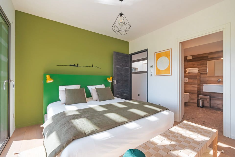 Bright bedroom with green accent wall and a touch of nature, ideal for a peaceful night’s rest.
