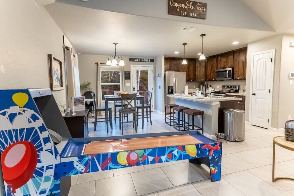 Open-concept living, dining, and kitchen — Canyon Lake vibes with skee-ball right in the mix
