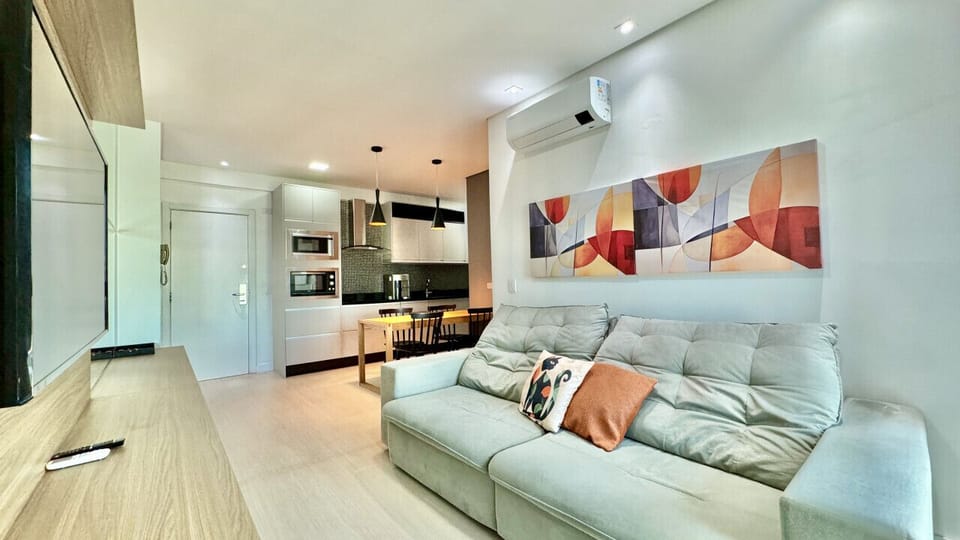 Sala com sofa cinza, Smart TV e quadro colorido na parede
