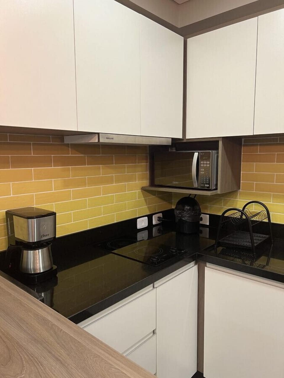 Cafeteira, micro-ondas, armários, lixo de pia, escorredor de louças, cooktop 2 bocas e exaustor.