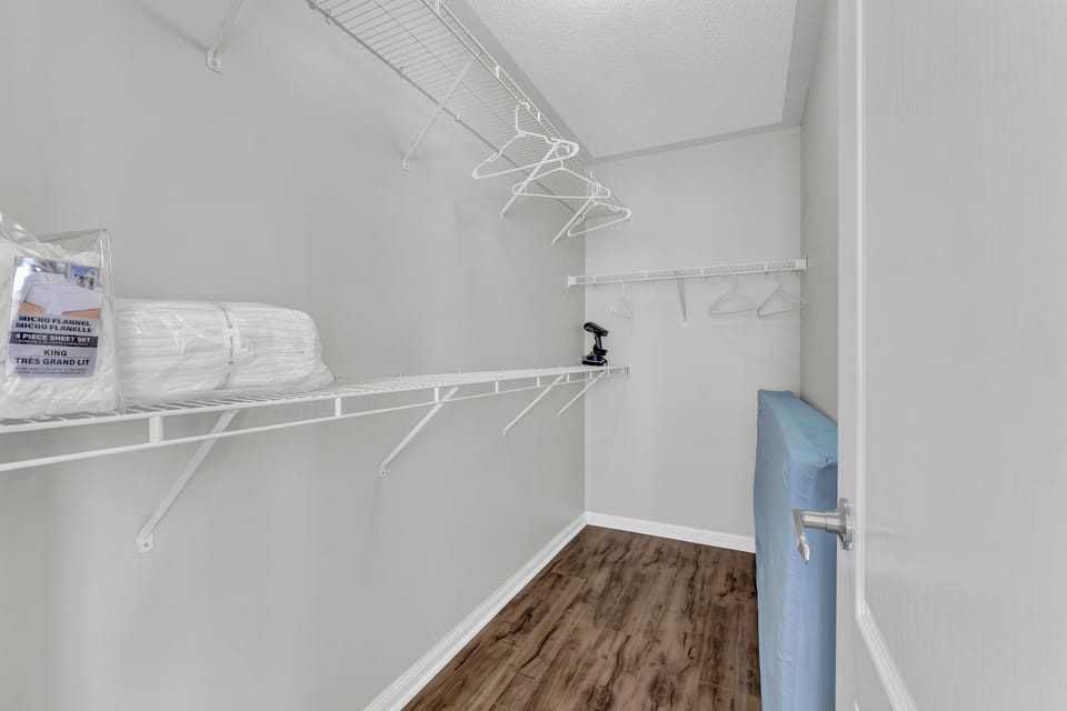 Spacious walk-in closet with wire shelving and wood-style flooring.