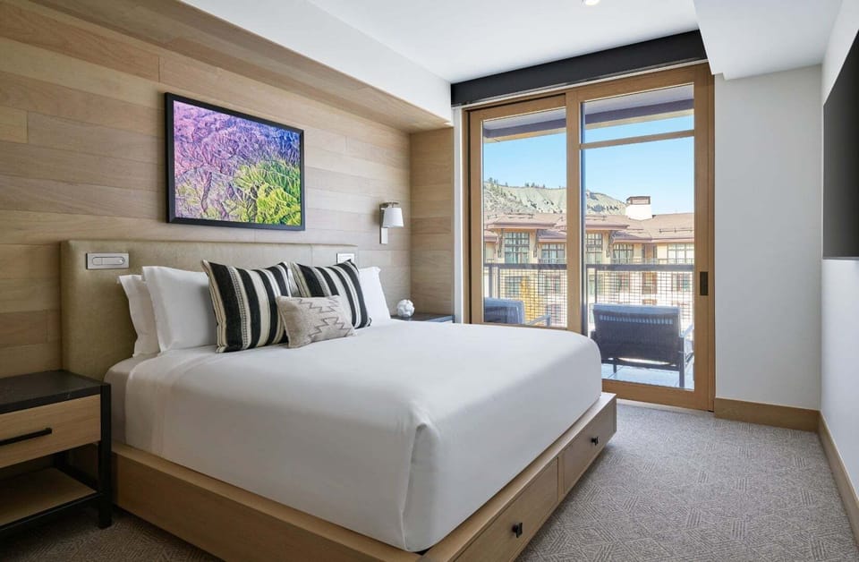 Plush king bed with leather headboard, integrated reading lights, and premium linens