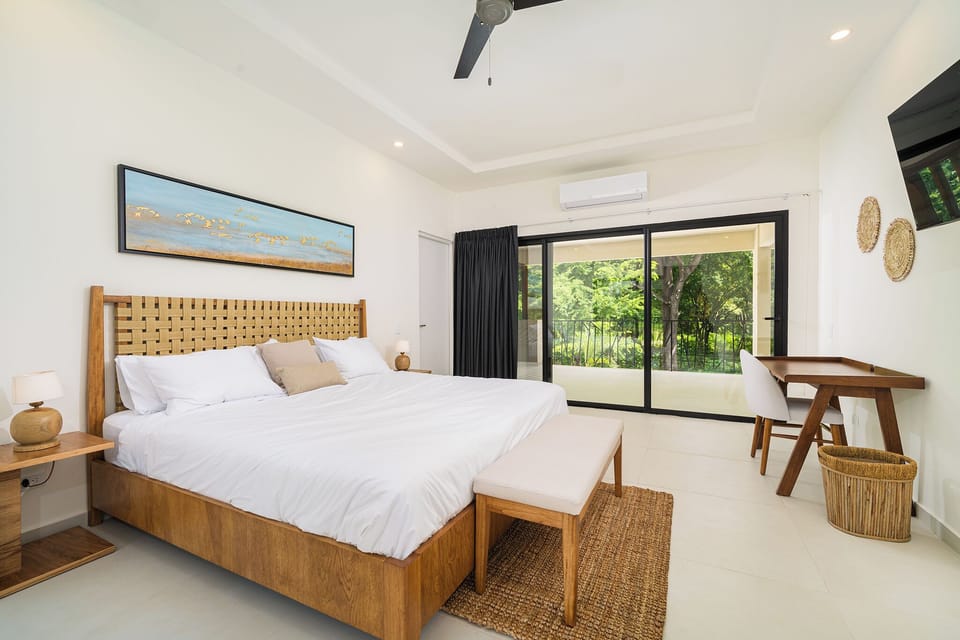 Bedroom on the second floor with a desk, TV, and access to one of two balconies.