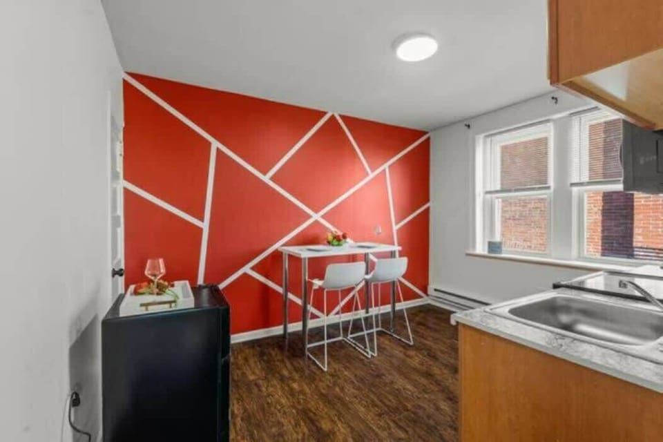 Indulge in a mealtime ambiance that's both understated and striking with this simple dining area set against a vibrant red wall