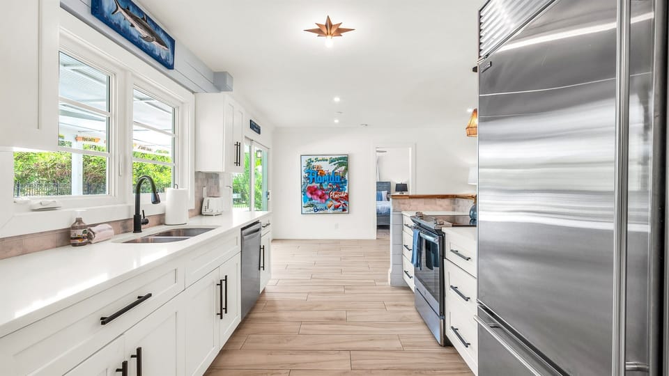 The fully stocked kitchen boasts a Sub-Zero fridge and acacia wood butcher block counters. A peninsula with seating provides the perfect spot for casual meals or morning coffee.