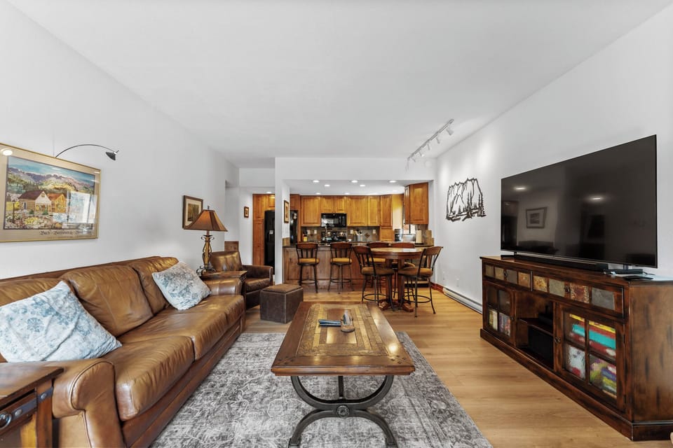 Living area with a large flat-screen TV, beautiful stone fireplace, queen sleeper sofa, and balcony access.