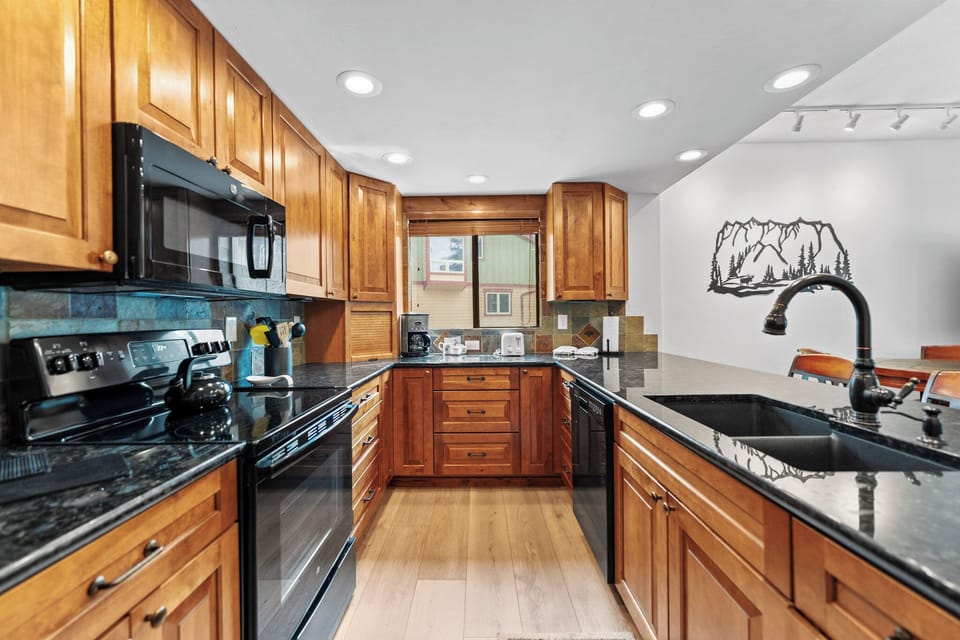 Full kitchen featuring granite countertops, a fridge with ice maker, and breakfast bar seating.