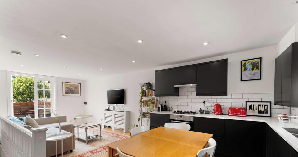 The warm wooden dining area and four sleek white chairs create a central spot for meals and socializing. It sits right on a beautiful patterned rug, which helps define the dining space within the larger room while keeping.