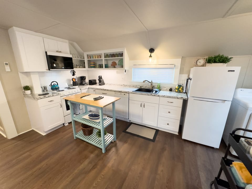 Kitchen is stocked with all of the basics for cooking including pots, pans, knife block, oil, spices, coffee, and tea.