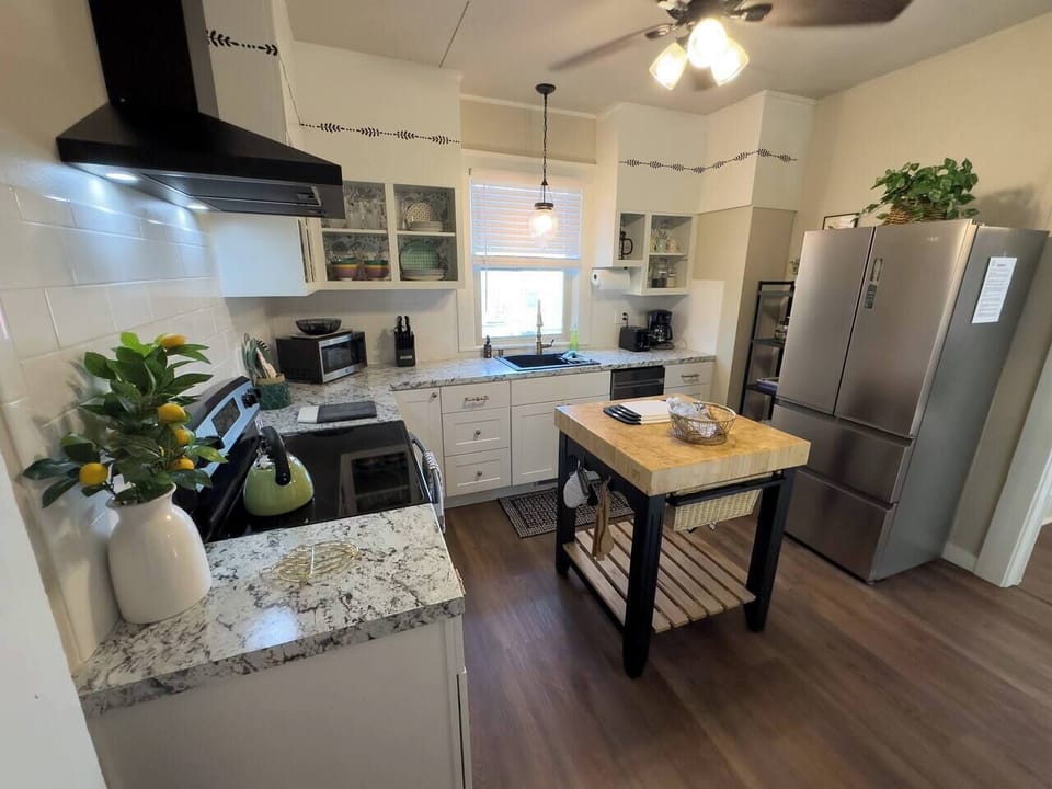 Kitchen features a butcher block table, large refrigerator/freezer, microwave, toaster, knife block, pots, pans, utensils, and more.