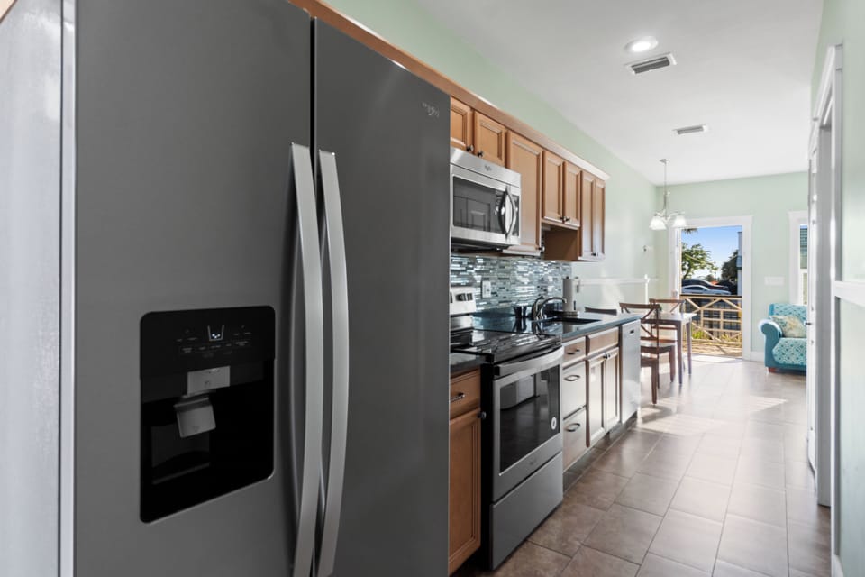 Your fully equipped kitchen awaits with modern stainless steel appliances, granite counters, and stylish backsplash—perfect for preparing vacation meals.
