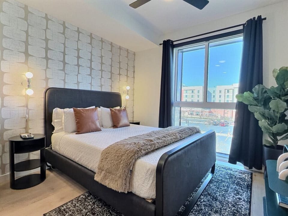 Relax in a cozy bedroom with city views inside a furnished apartment.