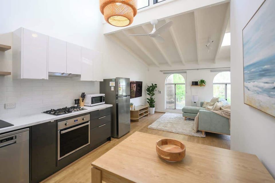Stylish open-plan living! Unwind on the comfy sofa with a smart TV, bathed in natural light. The modern, fully equipped kitchen features a stove, oven, microwave, and a lovely wooden dining table. Your perfect, inviting retreat awaits!