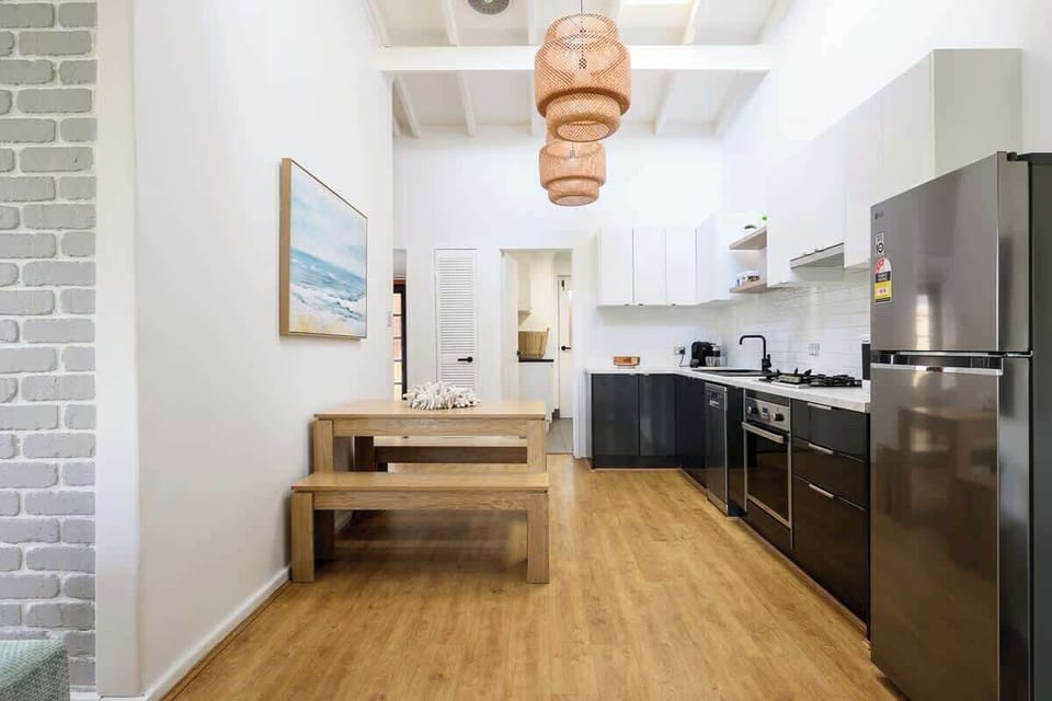  Enjoy cooking and dining with a beautiful wooden table and benches, ample cabinets for storage, a sleek oven and stove, a spacious refrigerator, a convenient sink, and even a coffee maker to start your day right.