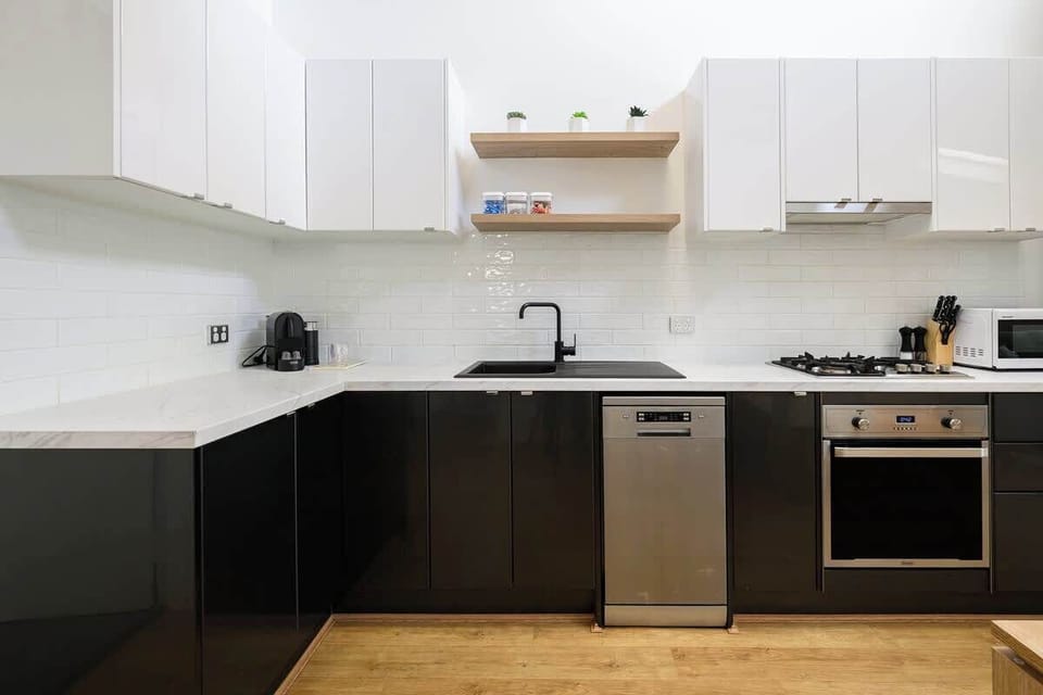 Enjoy the convenience of a modern electric oven, microwave, and dishwasher. Ample storage in the chic glossy white upper cabinets keeps everything organized for a seamless cooking experience.