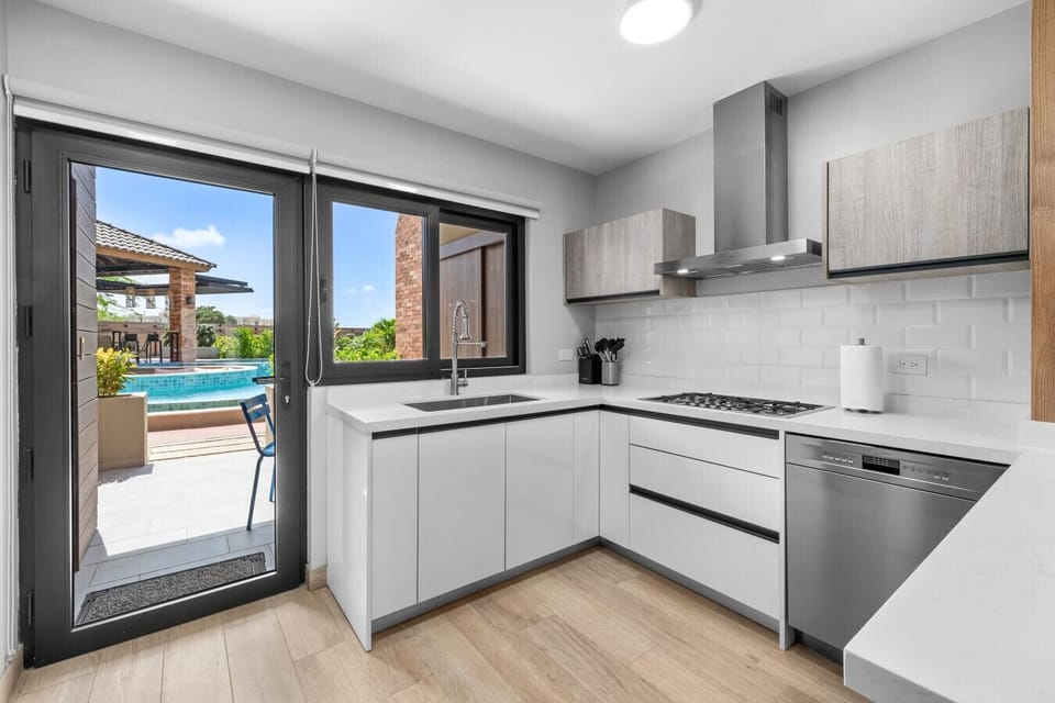 Check out this sleek kitchen with a view! Perfect for whipping up meals while enjoying the sunshine and poolside vibes just outside the door.