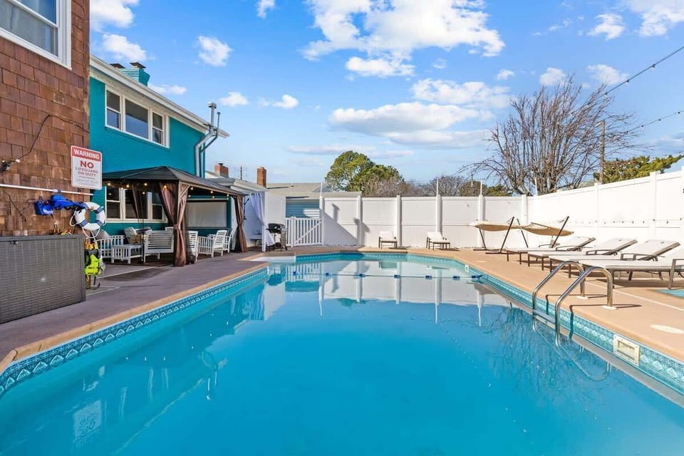 A sparkling outdoor pool invites you to relax and cool off under the bright blue sky. The fenced-in area offers privacy and plenty of lounging space. 