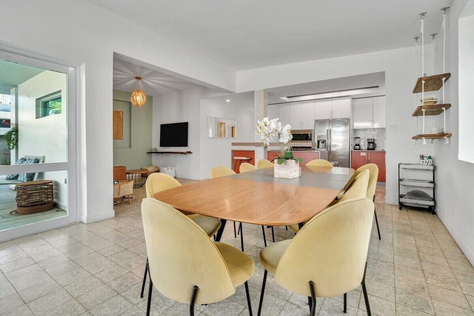 Bright dining area with a modern table, vibrant yellow chairs, and natural light!