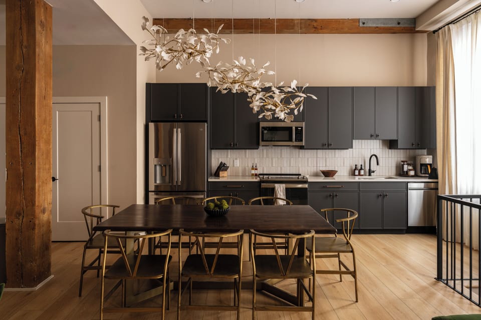 Bright kitchen/dining area with dark cabinets and gold chairs.