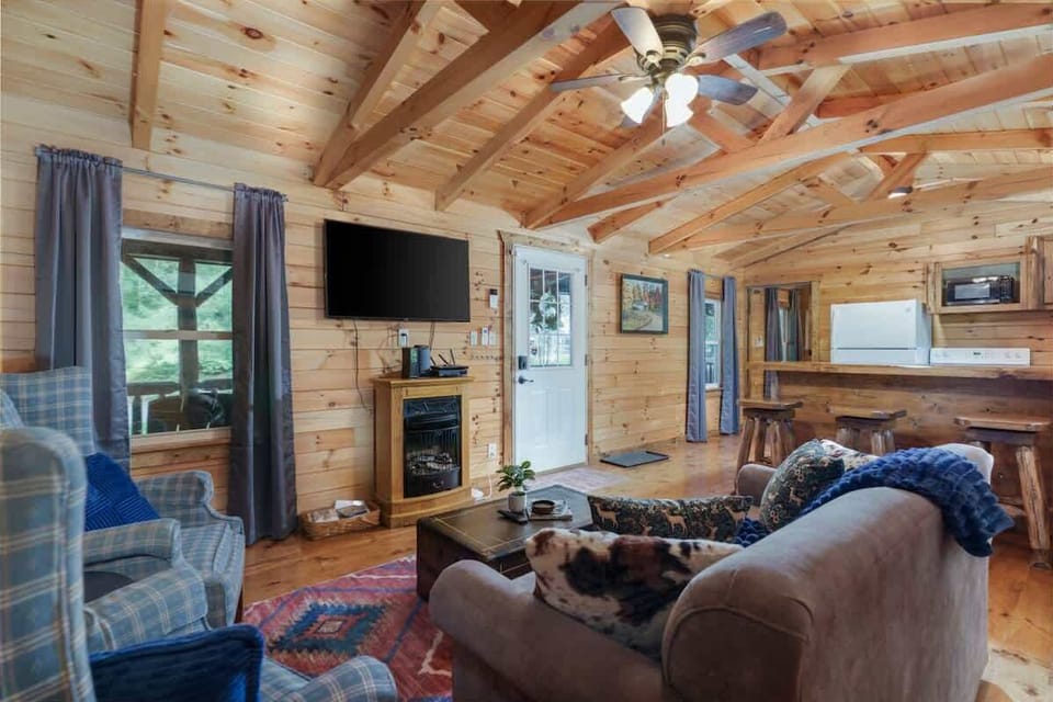 Relax in the warm wood-paneled living room w/ vaulted ceilings, comfy seating & a wall-mounted TV for cozy cabin nights