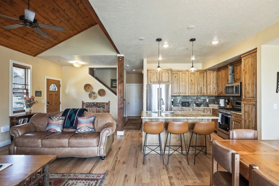 - Curl up on the leather couch surrounded by timber textures and earthy tones
- Cook and connect in a sleek kitchen with bar seating and mountain style flair
- Vaulted ceilings and wood beams bring in cabin coziness with a modern edge