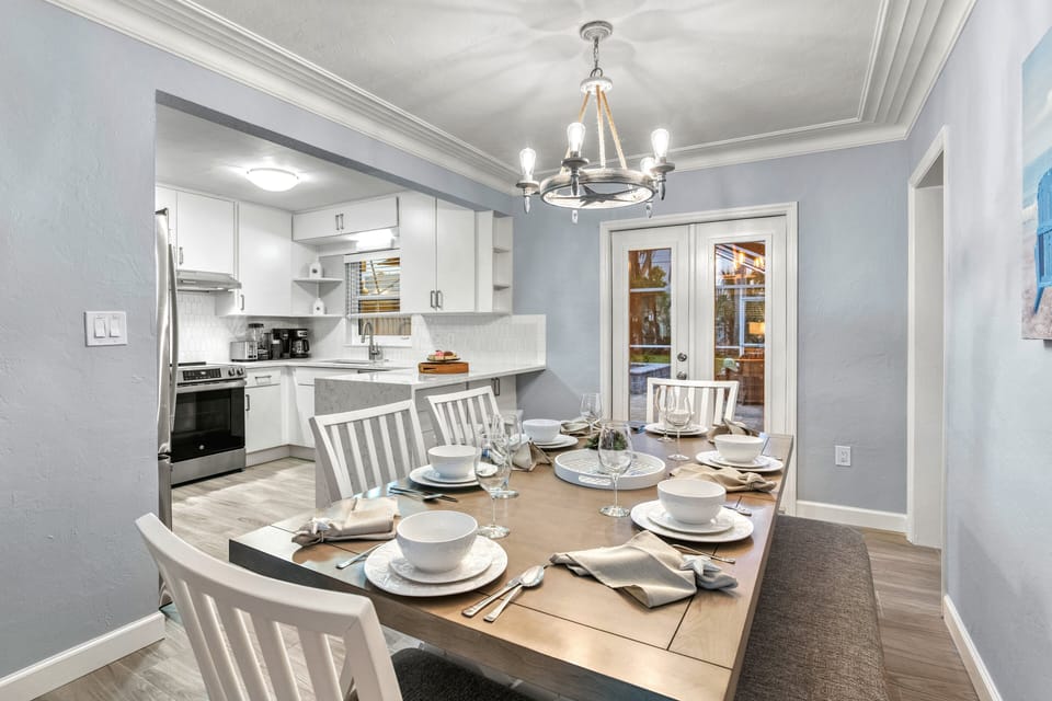 Dining room area with double doors to patio. View of kitchen on the left and the Den and Main Bedroom 1 on the right.