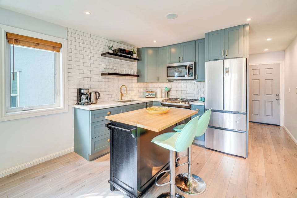Enjoy cooking in this bright, thoughtfully designed kitchen featuring sleek stainless steel appliances, soft blue cabinetry, and a cozy island perfect for morning coffee or casual meals together