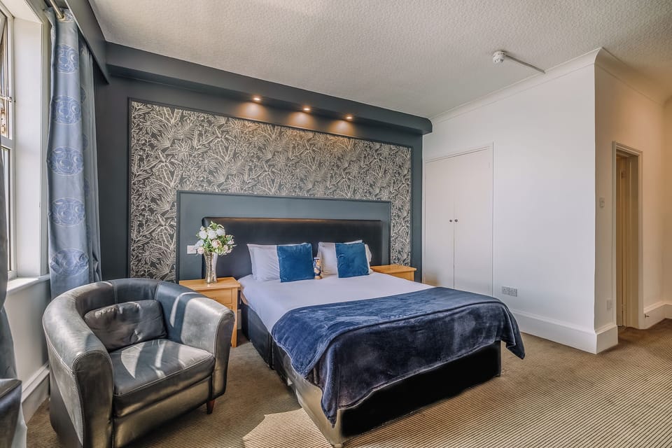 Lounge in luxury with statement wallpaper and a deep, comfy bed.