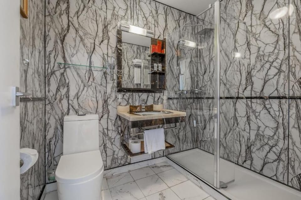 Refresh in a sleek marble-style bathroom with a spacious shower.