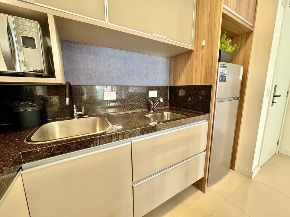 Cozinha compacta com bancada preta, fogao e geladeira integrados