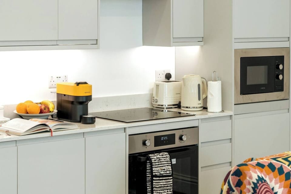 The kitchen features sleek white countertops and cabinets providing a clean and modern aesthetic. The induction cooker offers precise and efficient cooking, allowing you to prepare your favorite dishes with ease. 