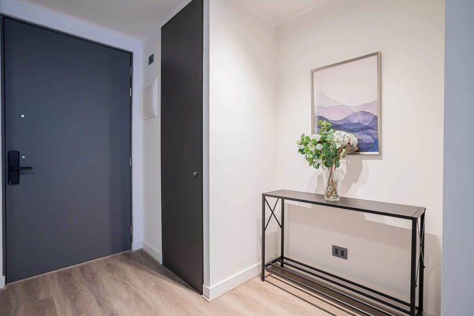 Welcome to a serene entryway with minimalist elegance, featuring chic decor and calming artwork.