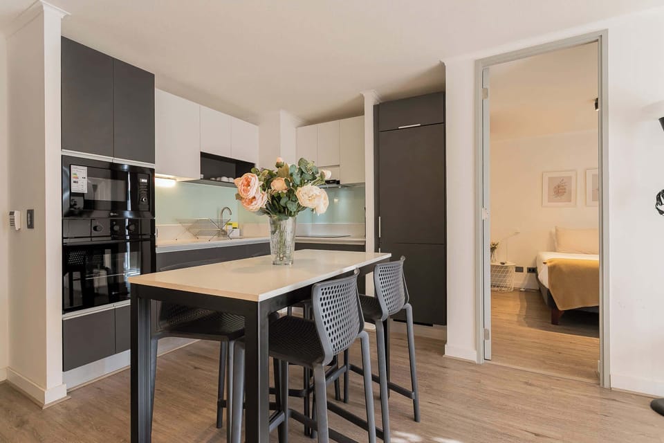 Sleek, modern kitchen with stylish dining island and cozy bedroom access—perfect for a comfortable stay.