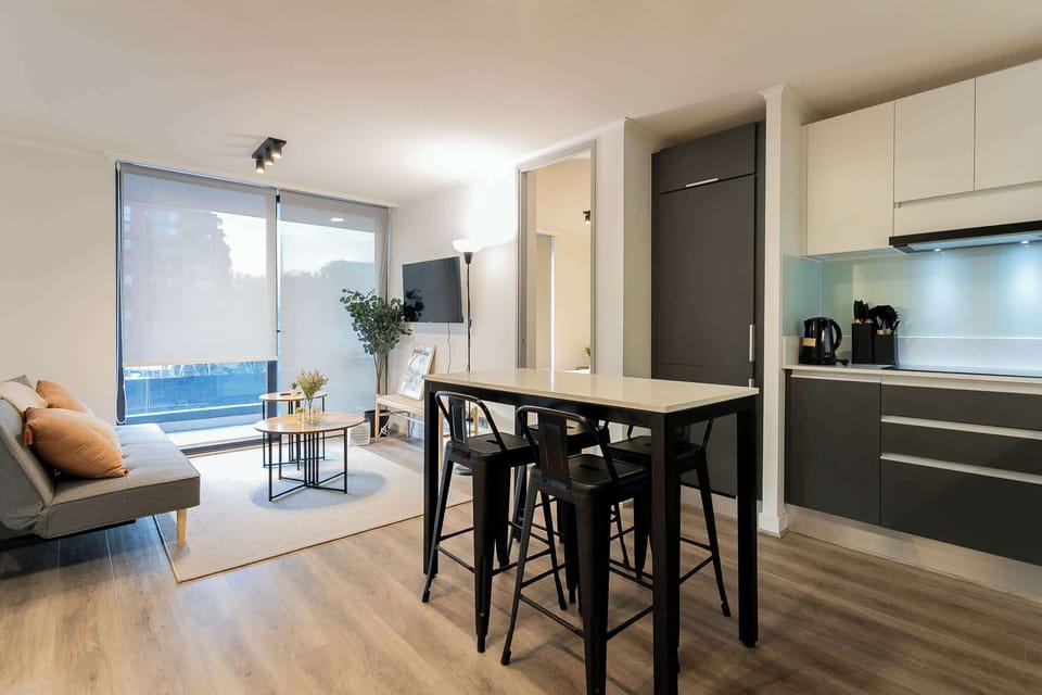 Stylish open-plan living area with modern kitchen, cozy seating, and abundant natural light—perfect for relaxing or entertaining.