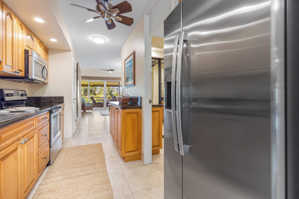 Sunlight fills your fully equipped kitchen, where stainless-steel appliances and warm wood cabinetry make every meal a joy to prepare.